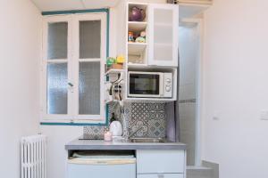 a small kitchen with white cabinets and a microwave at Chic Studio Apartment for 3 - La Villette! in Paris