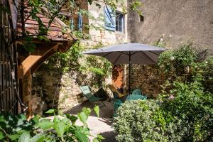 a patio with an umbrella and chairs in a garden at La Tour Aliénor, maison de caractère du XIVème siècle in Beynac-et-Cazenac