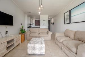 a living room with two couches and a flat screen tv at Azure Guesthouse in Ballito