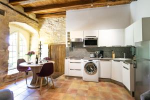 a kitchen with a washing machine and a table at La Tour Aliénor, maison de caractère du XIVème siècle in Beynac-et-Cazenac +29 photos