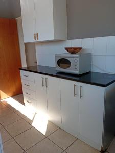 a kitchen with white cabinets and a microwave on a counter at Uptown Inn GuestHouse in Parys