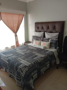 a bedroom with a bed with a blanket and a window at Uptown Inn GuestHouse in Parys