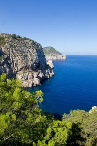 a large body of water next to a rocky cliff at Hacienda Na Xamena, Ibiza in Na Xamena