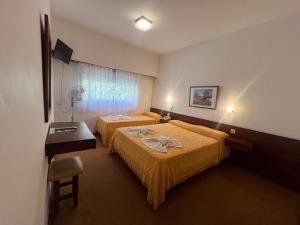 a hotel room with two beds and a desk at Hostería Santa Bárbara in Villa Gesell