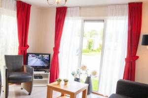 a living room with red curtains and a television at Chalet nr 43 in Molkwerum