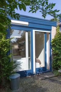 un cobertizo azul con una puerta corredera de cristal en BBBoekelo appartement en Boekelo