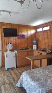 a kitchen with wooden walls and a table and a refrigerator at Alojamiento Parcela El Aromo in Paine