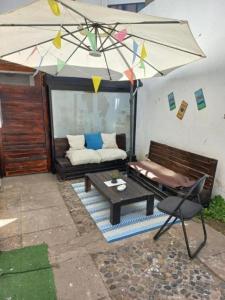 a patio with a couch and a table and an umbrella at Alojamientos Quintamar Viña in Viña del Mar
