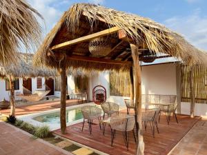 a patio with a table and chairs under a straw umbrella at Santuario San Agustín in Bajo de Arenal