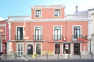 a pink building on the corner of a street at 7 Requinte HOSTel in Lisbon