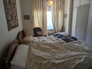 an unmade bed in a bedroom with a window at Rashas double room in London