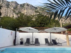 a group of chairs and umbrellas next to a swimming pool at Kuca za odmor Adriatica in Antovo