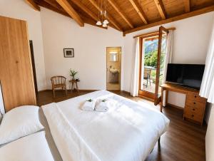 ein Schlafzimmer mit einem großen weißen Bett und einem Flachbildfernseher in der Unterkunft Alpine Hotel Reich in Cazis