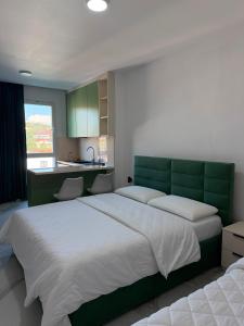 a bedroom with a large bed with a green headboard at Kurti Apartment in Golem
