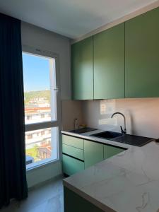 a kitchen with green cabinets and a large window at Kurti Apartment in Golem