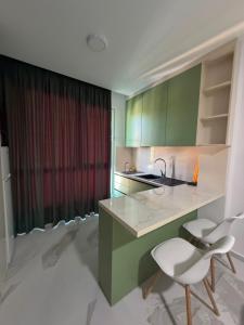 a kitchen with green cabinets and two white chairs at Kurti Apartment in Golem +6 photos