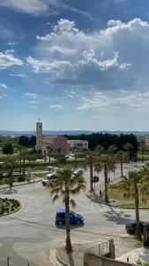 a parking lot with cars and palm trees and a building at Lushnja Apartament in Lushnjë