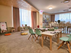 a classroom with tables and green chairs and a white board at In Grand Hotel & SPA in Bucharest