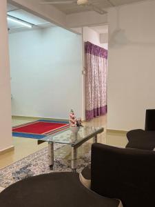 a living room with a glass table in a room at Homestay Jerantut in Jerantut