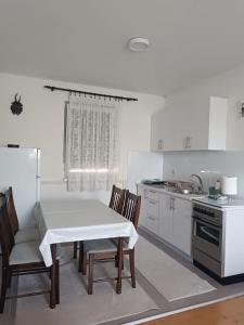 a kitchen with a white table and chairs and a stove at Vikendica Miki 2 in Bratunac