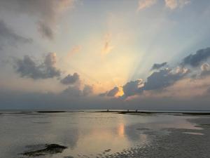 a sunset on the beach with the sun shining at Oasis Retreat Dhiffushi in Dhiffushi +2 photos