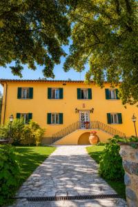 a large yellow building with a walkway in front at Relais Villa Sensano in Pignano