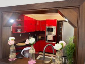 a kitchen with red cabinets and a sink with flowers at Leśny Domek in Piłka