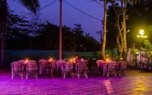 a group of tables and chairs with purple lights at Eve Resort in Patnem