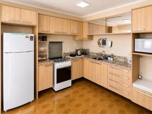 a kitchen with wooden cabinets and a white refrigerator at Guest house - Casa do Rogério in Caxias do Sul