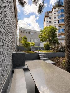 a bench next to a brick wall with a building at Guest house - Casa do Rogério in Caxias do Sul
