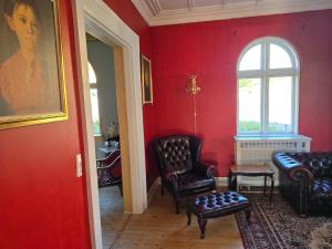 a living room with red walls and chairs and a window at Solvang in Assens