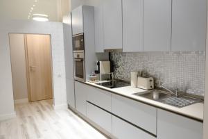 een keuken met witte kasten en een wastafel bij MaVa Apartments in Wenen