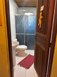 a bathroom with a toilet and a glass shower at Pousada Tiê-Sangue in Iporanga