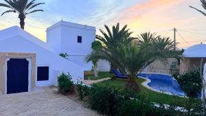 a white house with a pool and palm trees at Houch Taguermess in Taguermess