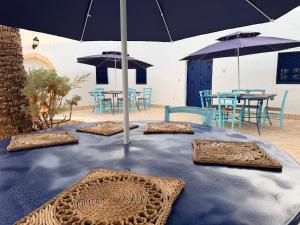 a blue table with umbrellas and tables and chairs at Houch Taguermess in Taguermess