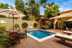 an outdoor pool with a table and chairs and an umbrella at Pousada Casa Cajá in Arraial d'Ajuda