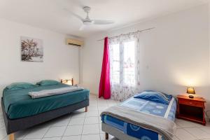 a bedroom with two beds and a window at Au Franciscea, climatiseurs, centre ville, sud in Saint-Louis