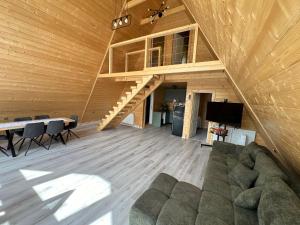 a living room with a couch and a table and a staircase at Crow`s Nest Murmur Măguri in Măguri