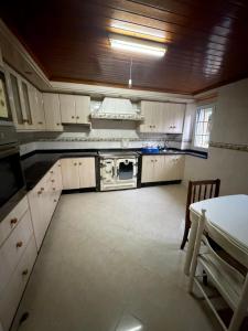 a kitchen with white cabinets and a stove at Casa Gallopin in Foz