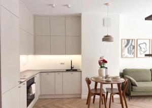 a kitchen with white cabinets and a table with chairs at GW Apart in Gorzów Wielkopolski