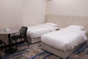 two beds in a room with a table and a chair at مـهادا Mehada in Taif