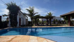 a swimming pool in front of a house with palm trees at Flecheiras Duplex com 3 suítes e piscina in Trairi