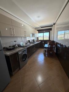 a kitchen with a washer and dryer and a table at Paraiso Costero Azla Tetouan in Azla