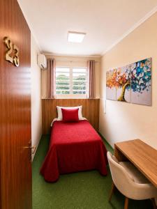 a bedroom with a red bed with a red blanket at Guest house - Casa do Rogério in Caxias do Sul