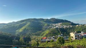 a view of a mountain with houses on it at Arupa Homestay in Ooty
