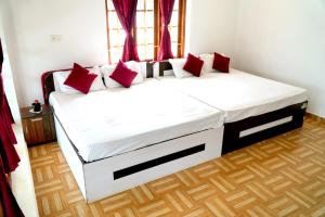 a bedroom with a large bed with red pillows at Arupa Homestay in Ooty