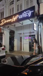 Eine Frau, die unter einem Schild mit der Aufschrift „Ein Traum“ hindurchging, verließ das Hotel. in der Unterkunft Dreamloft Hotel in Singapur