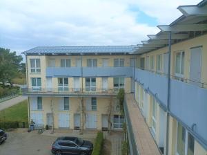 an apartment building with a car parked in a parking lot at Forum Marinar 38 in Bansin