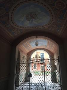 Palazzo Carasi Apartments في كريمونا: ممر مع بوابة ولوحة على السقف