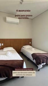 two beds in a room with a sign on the wall at Hotel Bom Gosto in Taiobeiras
